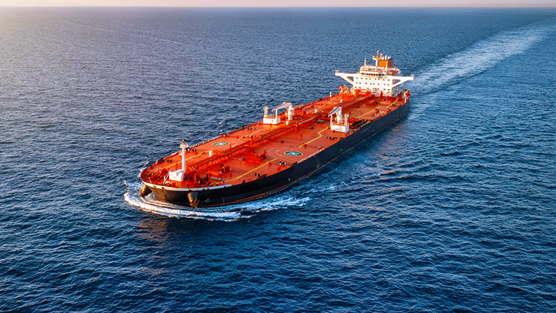 Aerial view of a heavy loaded crude oil tanker travelling over open ocean at sunset