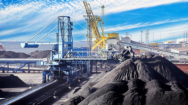 Coal harbour at maritime dry bulk cargo terminal, bucket wheel stacker reclaimer reloads coal onto an automatic conveyor belt.
