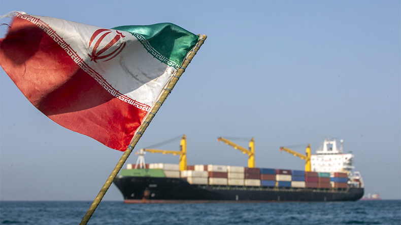 Iranian flag flutters in the wind as ships remain anchored on May 16, 2026 in the Strait of Hormuz near Larak Island